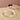 Two clear ribbed glass serving pieces on a beige stone surface. The round cake stand holds two dark red fruits while the round serving plate is empty.