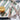 A knife and fork with brown wood-like handles resting on a stripe plate alongside a yellow kiwi fruit.