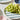 A close-up of green grapes on a blue and green striped side plate, set on a light gray surface with other plates and dishes partially visible.