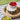 A round woven natural tray with a stack of two striped containers on it. The top container is full of raspberries while the bottom one has a cream lid on it. The tray is resting on a striped picnic mat laid on green grass.