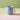 A matte light blue coloured ceramic mug with a braided handle, shown on a multi coloured background.