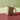 A matte light yellow coloured ceramic mug with a braided handle, shown on a multi coloured background.