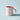 A classic ceramic mug with a pale pink exterior and a bright red interior with a curved handle. Photographed on a sky blue coloured background with strong shadows.